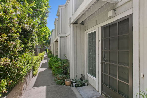 Front view of a row of townhouses with a narrow pathway and greenery.