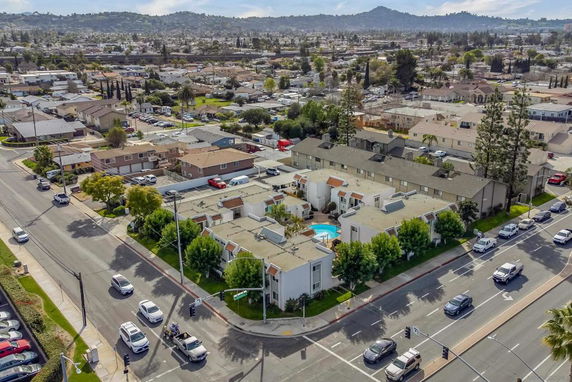 Aerial view of a residential area with multiple houses, roads, and a small swimming pool visible in the center.