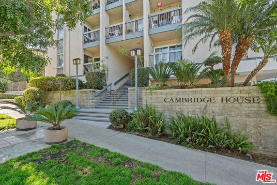 Front view of a multi-story building with balconies and stairs leading to the entrance.