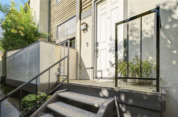 Entrance view of a house with a small porch and stairs leading to the front door.