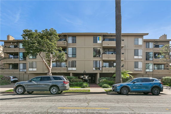 Front view of a multi-story residential building with balconies and a central entrance.