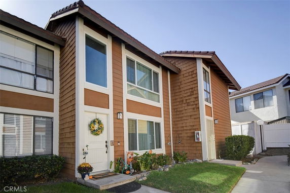 Front view of a two-story townhouse with shingle siding and large windows.