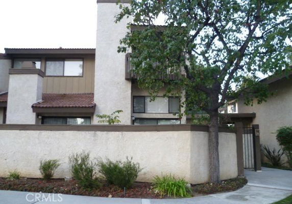 Front view of a multi-story house with stucco exterior and a small walled courtyard.