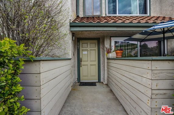 Front view of a house with a covered entry and a small patio area.