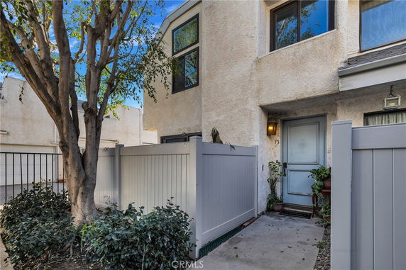 Front view of a two-story townhouse with a fenced entryway.