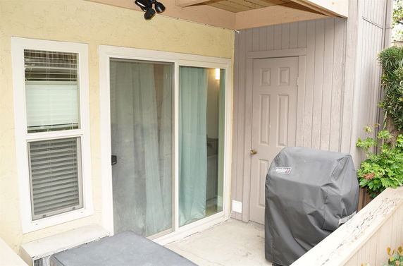 Outdoor area with a sliding glass door and covered grill.