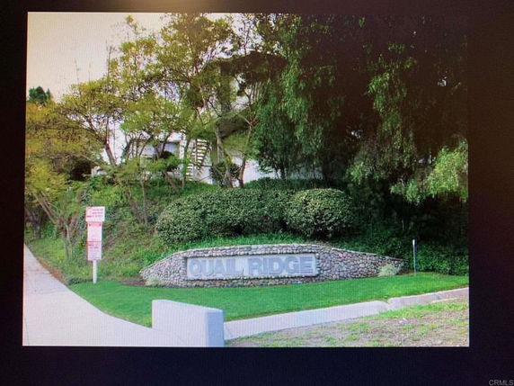Front view of a building with trees and a stone sign reading 'Quail Ridge'.