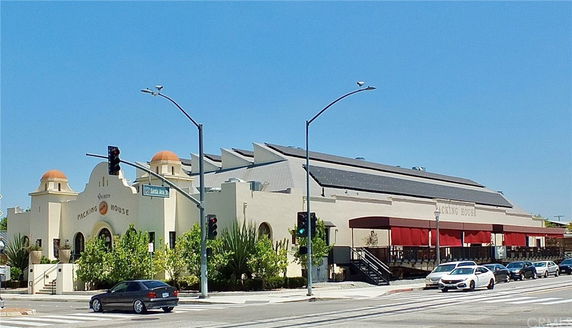 Front view of a large building with solar panels on the roof and distinctive architectural features.