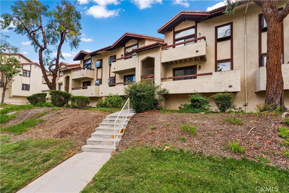 Front view of a multi-story residential building with balconies and sloped roofs.