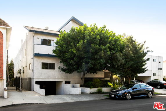 Front view of a multi-story residential building with parking entrance.