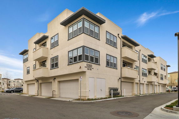 Front view of a multi-story apartment building with balconies and garages.