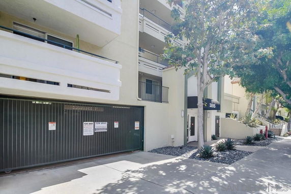 Front view of a multi-story building with balconies and a gated entrance.