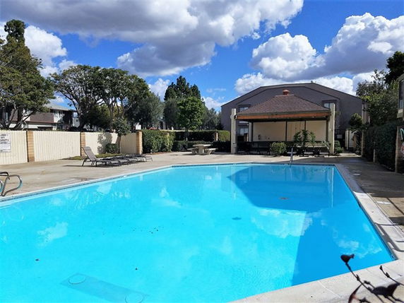 Outdoor swimming pool with a building in the background.