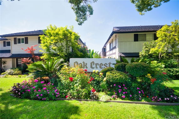 Front view of residential buildings with a sign reading 'Oak Crest' surrounded by landscaping.