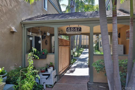 Front view of a residential entryway with plants and a walkway.