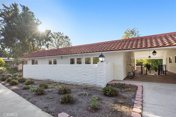 Front view of a house with terracotta tile roof and carport.
