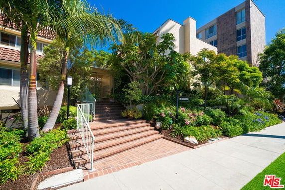 Front view of a multi-story building with a brick entrance and lush landscaping.