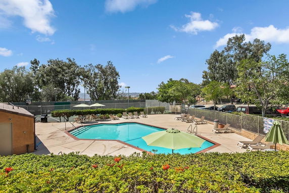 Outdoor swimming pool with lounge chairs and umbrellas.