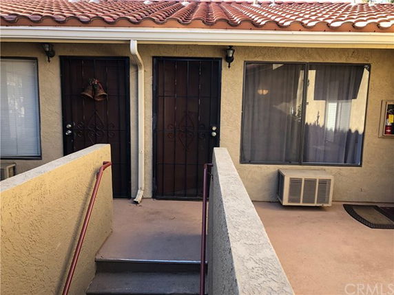 Front view of a building with two doors and a window beneath a tile roof.