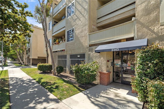Front view of a multi-story apartment building with balconies and an entrance canopy.