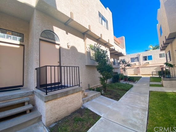 Front view of a multi-story residential building with staircases leading to individual entrances.