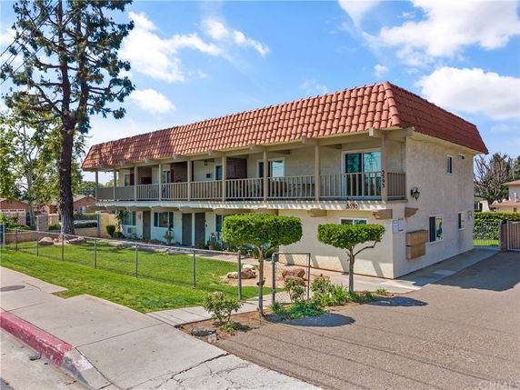 Front view of a two-story building with a tile roof and balcony.