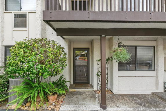 Front view of a building entrance with a small covered porch area and hanging plants.