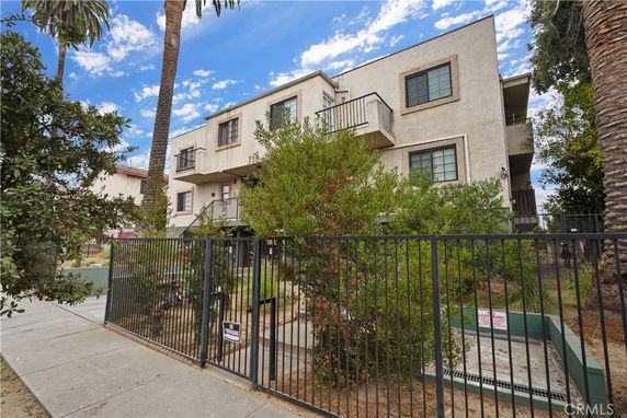 Front view of a multi-story residential building with balconies and a gated entrance.