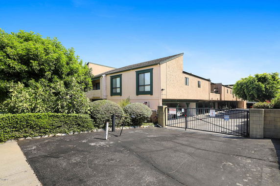 Outdoor parking area of a residential building with gated entrance.