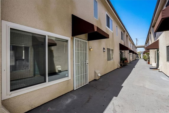 Front view of a two-story apartment building with awnings and windows lining a walkway.
