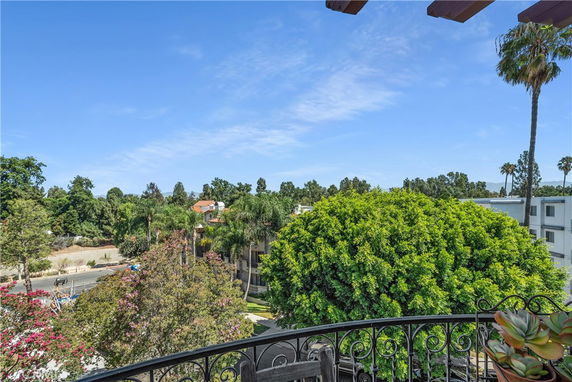 Panoramic view of trees and buildings from a balcony.