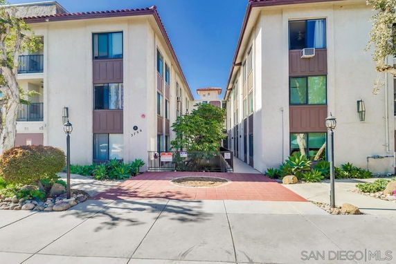 Front view of a multi-story residential building with large windows and a tiled entrance path.