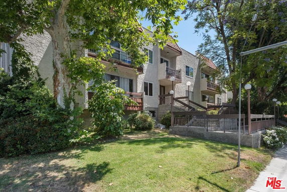 Front view of a multi-story residential building with balconies and a landscaped garden.