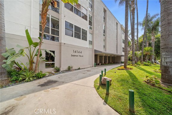 Front view of a multi-story building with large windows and a driveway leading to the entrance.