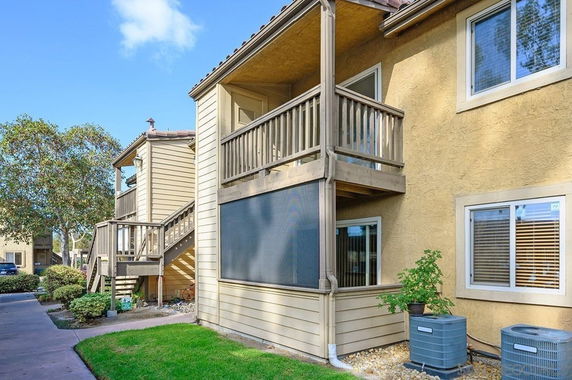 Front view of a two-story building with a wooden balcony and staircase.