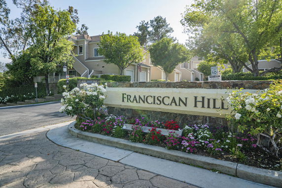 Front view of a residential complex with a sign reading 'Franciscan Hill'.