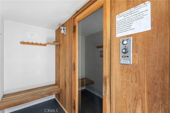 Indoor sauna with wooden benches and control panel.