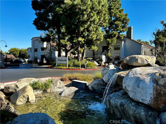 Front view of a residential building complex with an entrance sign and surrounding landscaping.