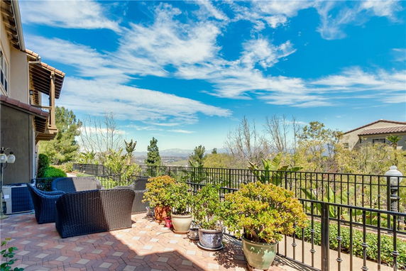 Outdoor patio area with seating, plants, and view of distant landscape.