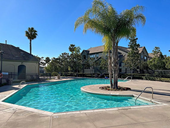 Outdoor swimming pool with surrounding patio and nearby buildings.