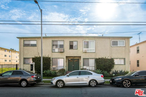 Front view of a two-story apartment building with parked cars.