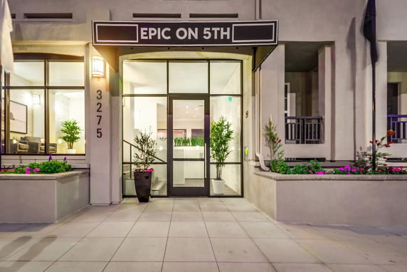 Front view of a building entrance with glass doors and potted plants.