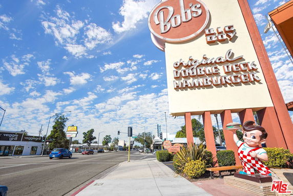 Front view of a restaurant with a large sign featuring a statue and text advertising hamburgers.