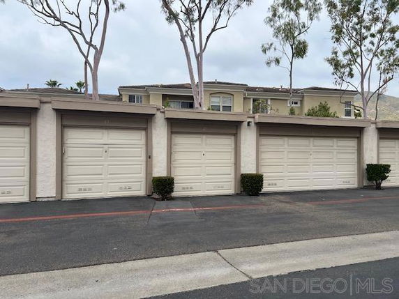 Outdoor parking area with multiple garage doors in front of a residential building.