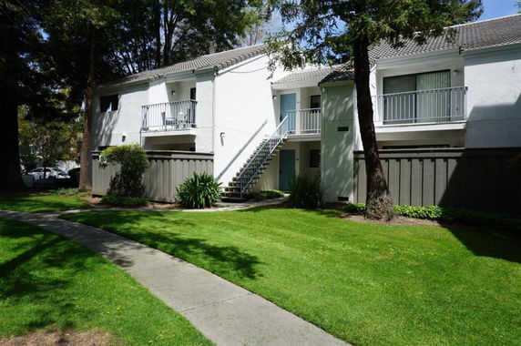Front view of a two-story apartment building with exterior stairs and small balconies.