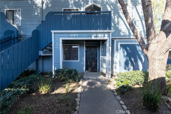 Front view of a multi-story building with blue siding and a staircase.
