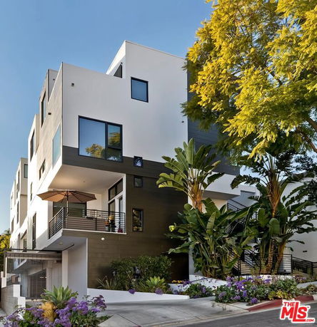 Front view of a modern multi-story building with balconies and large windows.