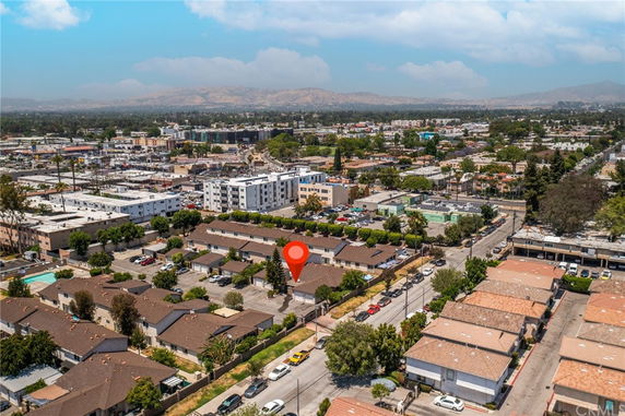 Aerial panoramic view of a neighborhood with various residential buildings and a bustling cityscape in the background.