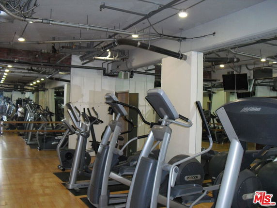 Gym area with multiple elliptical machines and mirrors on the wall.