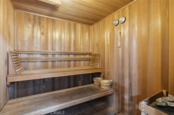 Interior view of a wooden sauna room with benches and a heater.